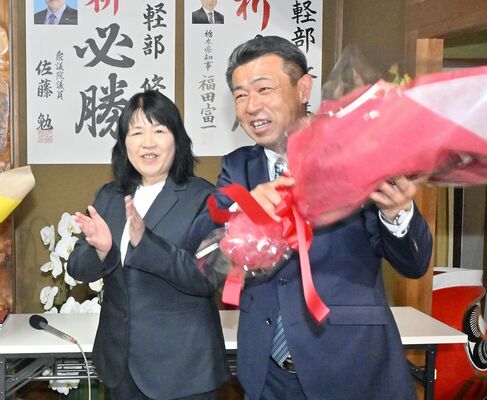 初当選が確実となり、支持者から花束を受け取る軽部修氏（右）＝９日午後７時35分、市貝町文谷、近藤文則撮影