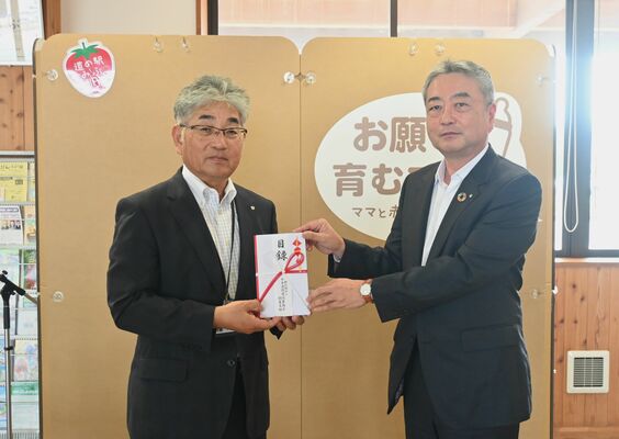簡易設置型授乳室の前で目録を受け取る小菅町長（左）