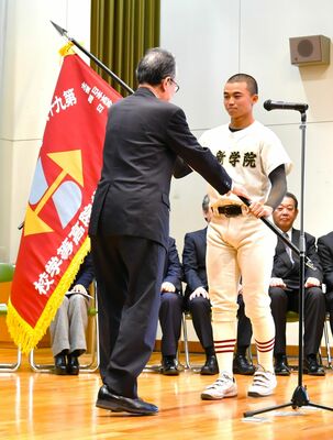 船田学院長（左）から選抜旗を受け取る作新の小森主将＝２月16日
