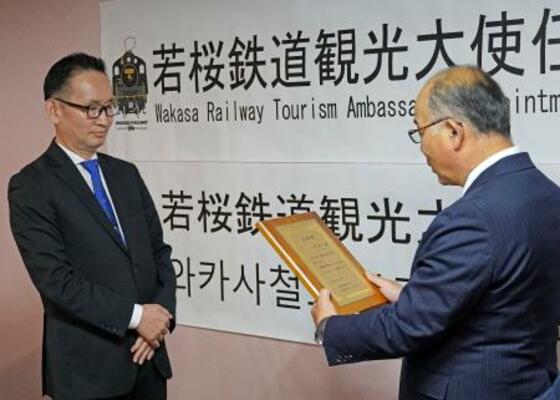　若桜鉄道の矢部雅彦専務（右）から観光大使の任命状を受け取る尹熙一さん＝１１月、韓国・大田（共同）