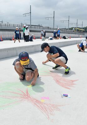 舗装前の道路に絵を描く子どもたち