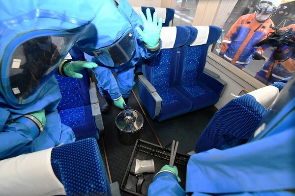 防護服をまとい、列車内の座席下で不審物を検索する県警機動隊員＝17日午前10時55分、日光市松原町