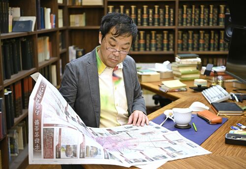 宇都宮空襲の特別紙面をじっくりと読む門井さん＝2025年12月、大阪府内、森田大地撮影