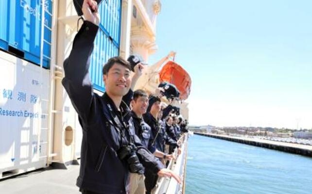 オーストラリア西岸のフリマントルを出港し、観測船「しらせ」の甲板で見送りに来た人たちに帽子を振る隊員ら=8日(南極観測隊同行記者撮影)