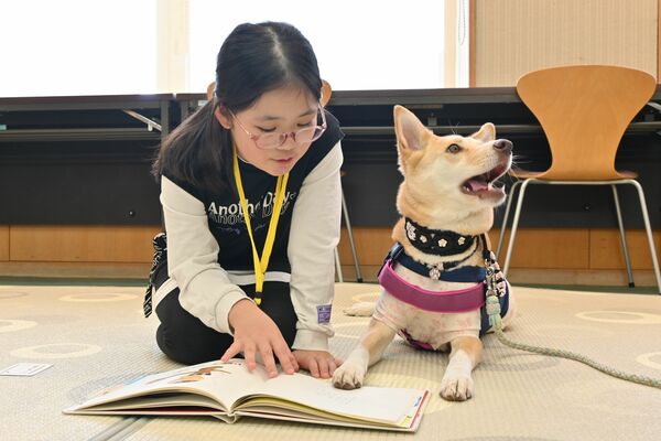 セラピー犬に読み聞かせをする子ども＝６日午後、鹿沼市睦町