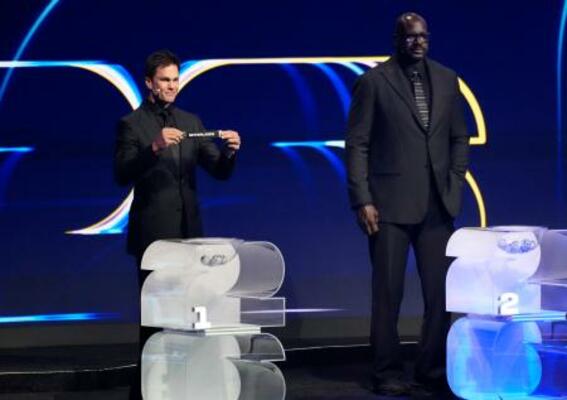 　サッカーＷ杯北中米３カ国大会の組み合わせ抽選で、第１ポットのくじを引くトム・ブレイディさん。右はシャキール・オニールさん＝５日、米ワシントン（共同）