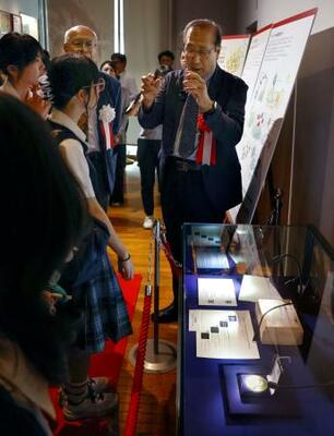 「金属有機構造体」の研究成果を特別展示するコーナーで、高校生の質問に答える京都大の北川進特別教授(右)=19日午後、京都市の京都大総合博物館