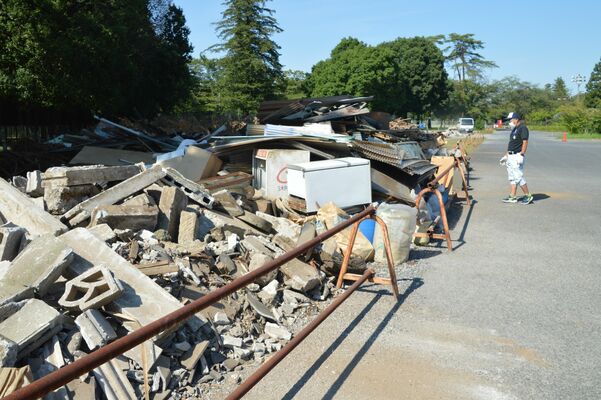 野木町総合運動公園に設置された災害ごみ仮置き場。壊れた住宅の一部などが積み上がっている＝24日午後３時、野木町佐川野