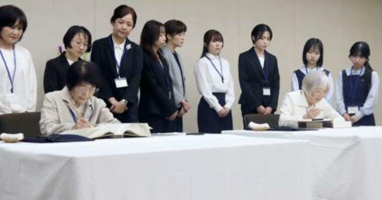 　原爆死没者名簿に記帳する中本信子さん（手前左）と大川純子さん。後方は一般公募で選ばれた記帳者ら＝４日午前、広島市役所