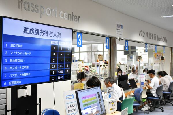 パスポート申請の待ち人数が15人と表示され、混雑する窓口＝１日午前10時20分、宇都宮市パスポートセンター