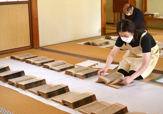 貴重な古書を丁寧に広げて虫干しする職員