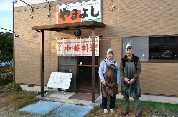 店の前に立つ吉森保さん（右）と妻の由紀子さん