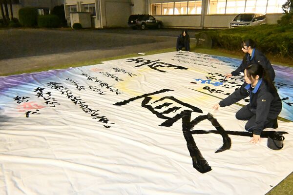 はけとペンキで文字入れをする生徒ら