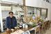 店主の長谷川さん。カウンターには開店の祝い花が並ぶ