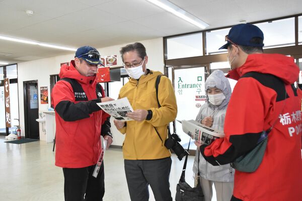 山麓駅を訪れた人にチラシを配る署員