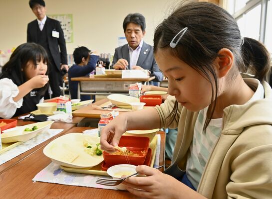 チーズフォンデュをクラッカーに付けて味わう児童