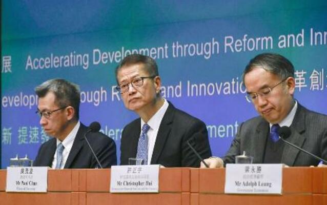 記者会見で財政予算案について説明する陳茂波財政官(中央)=2月、香港