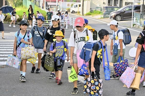 厳しい暑さの中、夏休みの宿題などを手に登校する児童たち＝１日午前７時35分、真岡市台町