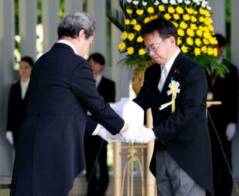 千鳥ケ淵戦没者墓苑で開かれた拝礼式で、新たに納骨する遺骨を受け取る上野厚労相=25日午後、東京都千代田区