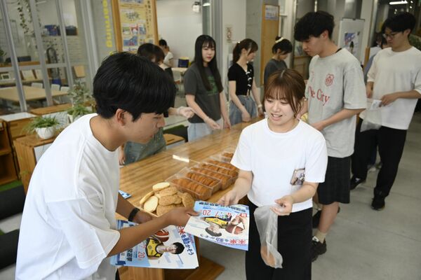 宇都宮大の学生に参院選のチラシを配るボランティア（左）＝２日午後、宇都宮市陽東７丁目