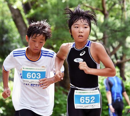 女子６年で優勝した大道（清原北、右）。男子６年を制した月井（高林）と激しく競り合う＝那珂川河畔公園