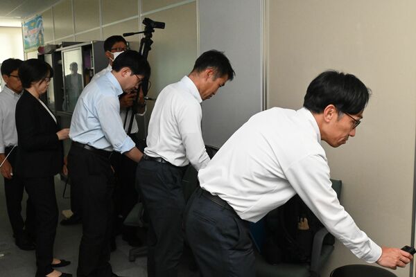 探知機を使って盗撮カメラを模した機器を探す県教委職員=25日午後2時10分、県庁南別館