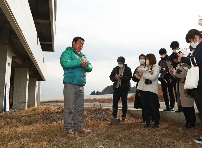 高野会館の前で被災当時の状況を説明する佐々木さん=南三陸町(河北新報社提供)