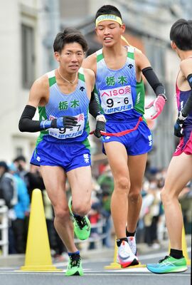 ６区の中村（右）からたすきを受け走り出す７区の菊地＝広島市内
