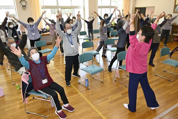 講師役（手前）の動きに合わせて体操する参加者たち

