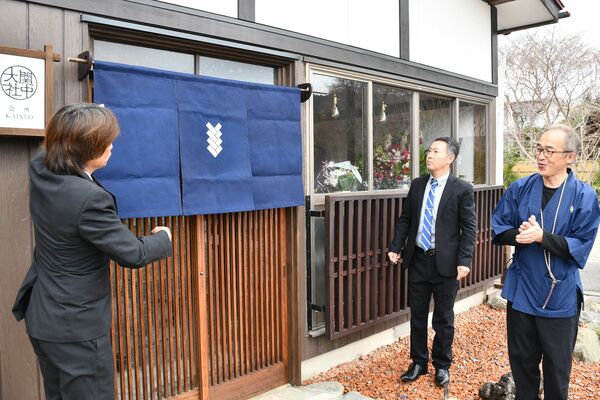 「大関社中 会所」の入り口に黒羽藍染めののれんを掛け、開業を祝う関係者ら