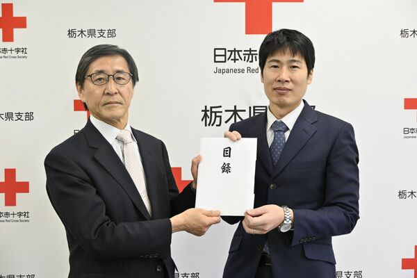 日赤県副支部長の岩佐氏（右）に救援募金の目録を手渡す若菜社長＝11日午前、宇都宮市若草１丁目