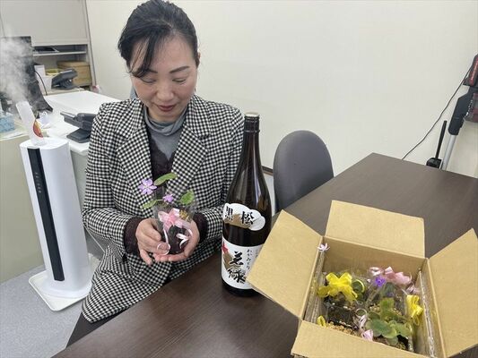 炊き出しのお礼として、被災者から贈られた日本酒や雪割草を眺める入江さん＝２月下旬、宇都宮市