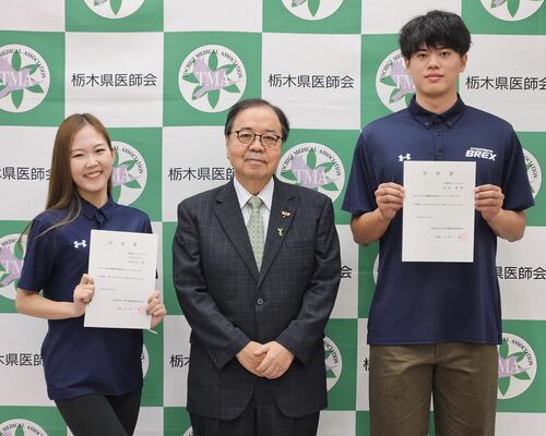 小沼理事長（中央）からサポーターに任命された村岸選手（右）とＨＩＫＡＲＩさん（左）＝３日午後、宇都宮市駒生町