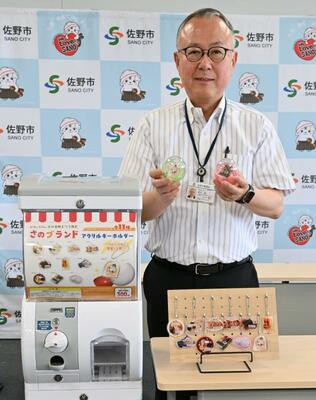市オリジナルのアクリルキーホルダーを紹介する金子市長