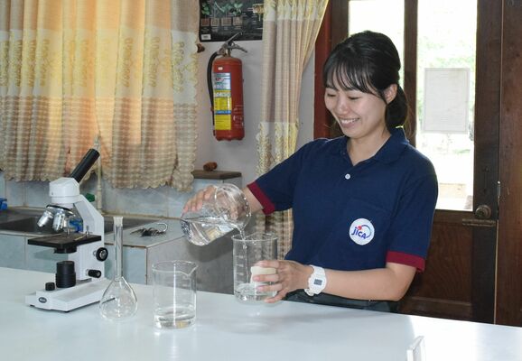 理科の実験器具を手にする宮川さん＝８月中旬、パクセー教員養成校