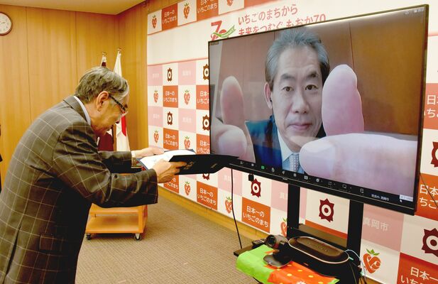 オンラインで委嘱状のやりとりをする石坂市長（左）と小出さん