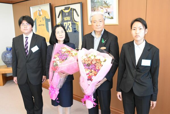 県農業大学校の学生からカーネーションを受け取った福田知事（右から２人目）と妻の喜江子さん（同３人目）＝10日午前、県庁