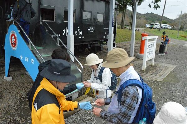 下野中川停車場で記念の硬券切符にはさみを入れて車掌車に乗り込むツアー参加者