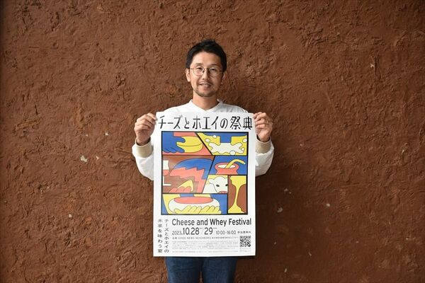 「チーズとホエイの祭典」のポスターを持つ山川さん
