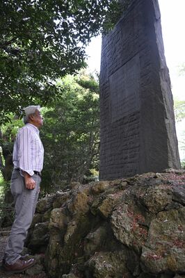 江曽島地区の戦没者慰霊碑を見つめる石浜さん。碑には叔父の名前が刻まれている＝４月下旬、宇都宮市内
