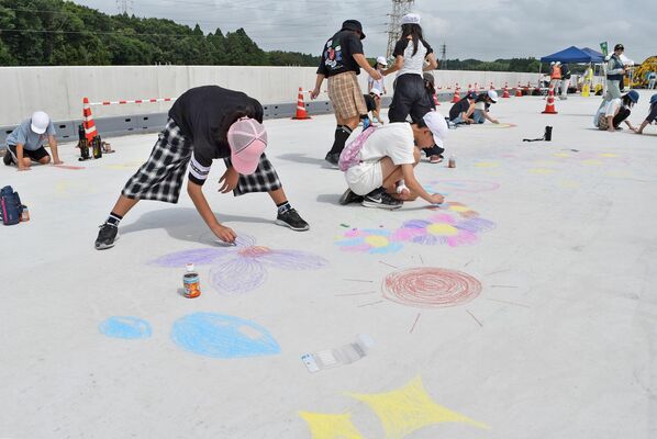 舗装前の道路に絵を描く子どもたち
