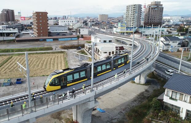 平石－宇都宮大学陽東キャンパス間の高架を試運転するＬＲＴの車両＝１７日午前１１時５分、宇都宮市平出町、ドローンから