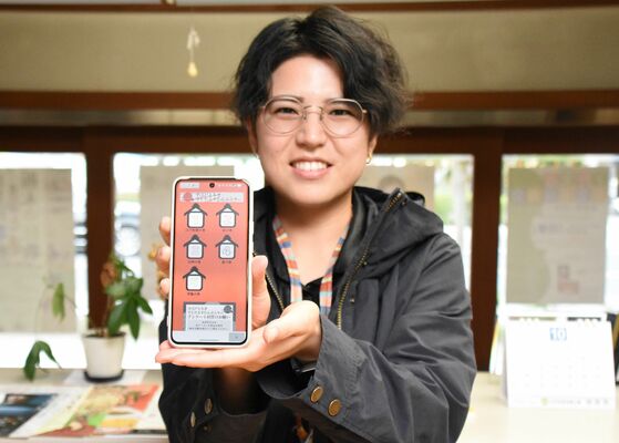 スタンプラリーの画面を掲げる押見さん