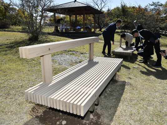 寄付された木製ベンチを確かめる関係者ら