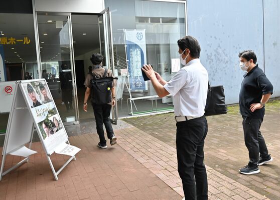 映画の看板を撮影しながら会場に入る招待者＝23日午前、宇都宮市竹下町