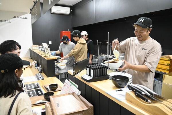 サービスのトッピングを盛り付ける小山さん（右）