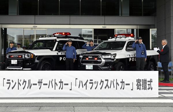 中村さん（右端）によって寄贈されたパトカー仕様の（左から）トヨタ「ランドクルーザー」と「ハイラックス」＝午後１時30分、県庁