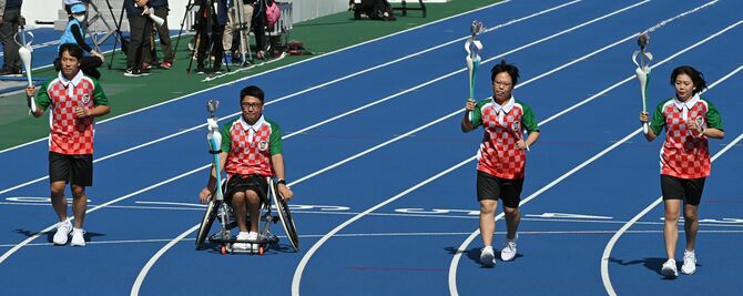 国体選手によって炬火が分火され、障スポ選手(中央2人)に引き継がれた=11日、午前10時50分、宇都宮市のカンセキスタジアムとちぎ