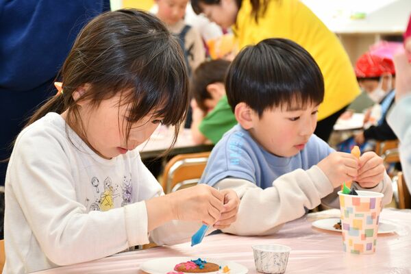 チョコペンを使ってクッキーに飾り付けをする児童