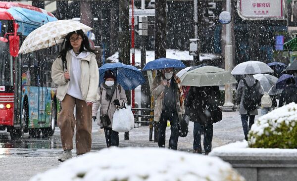 雪の中、通勤する人たち＝19日午前7時35分、宇都宮市駅前通り2丁目